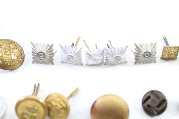 Discover a unique collection of 31 original uniform pieces, buttons, badges, overlays, and buckles