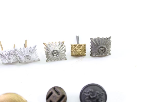 Discover a unique collection of 31 original uniform pieces, buttons, badges, overlays, and buckles