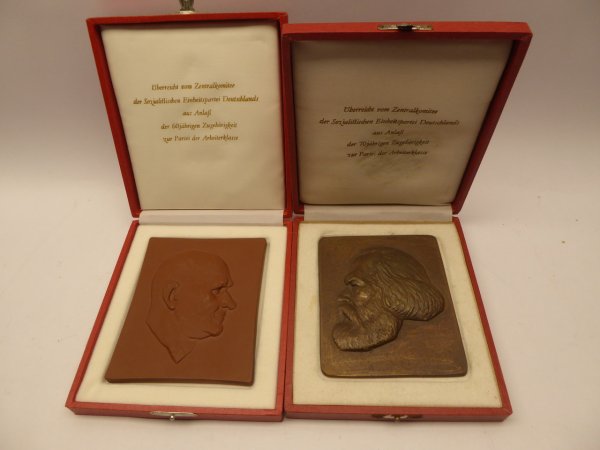 Two GDR plaques - presented by the Central Committee of the SED - in a case, Meissen and bronze